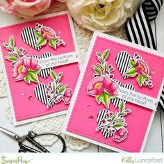 two cards with flowers on them sitting next to some scissors and pink flowers in the background