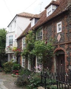 a cobblestone street lined with houses and flowers