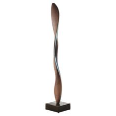 a tall metal sculpture on top of a wooden base