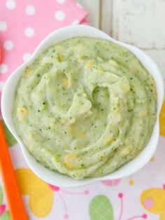 a white bowl filled with green sauce next to a spoon and napkin on top of a table