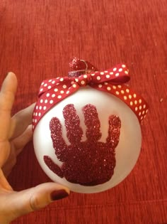 a handprinted ornament is being held by a woman's hand