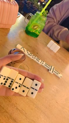 a person is holding dominos in their hand at a table with other dominos on it