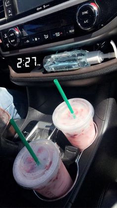 two drinks sitting in the center console of a car