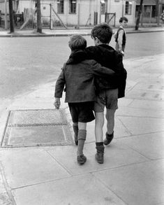 two young boys walking down the sidewalk with their backs to each other