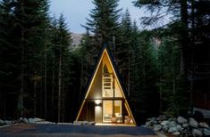 a small cabin in the middle of a forest at night with lights on it's windows