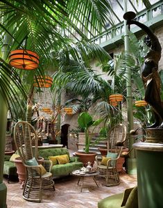 a room filled with lots of green furniture and palm trees in the middle of it