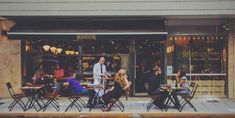 a group of people sitting at tables in front of a restaurant