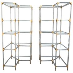 a pair of metal and glass shelvings with gold trimming on each shelf