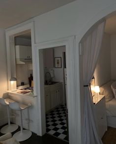 an open door leading to a kitchen and living room with checkerboard flooring