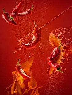 hot peppers being tossed into the air with fire and water splashing around them on a red background