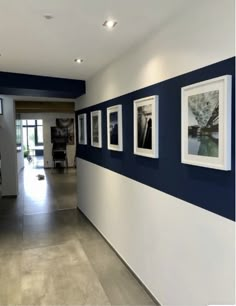 an empty hallway with pictures on the wall and tables in front of it, along with chairs