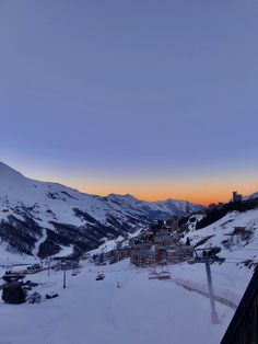 the sun is setting over a ski resort in the mountains with snow on the ground