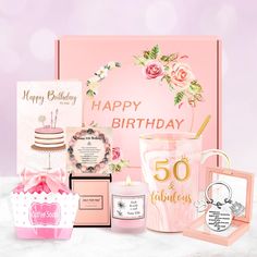 a pink birthday gift box with candles, greeting cards and other items for someone's 50th