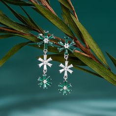 Every winter, we look forward to the first sight of a snowflake. Enjoy the beauty year round with these bewitching sterling silver snowflake earrings. The darling design highlights different-sized snowflakes made of twinkling white and green stones, which enhances her beauty and refreshes her spirit. Wear this dangle earrings while gathering by the fireplace in winter holidays, or simply to feel cooler on a hot summer day, or just to add a touch of wintry magic to your everyday look. You can mat Snowflake Earrings, Green Stones, Silver Snowflakes, Sterling Silver Drop Earrings, Spirit Wear, Silver Drop Earrings, Green Stone, Winter Holidays, Emerald Cut