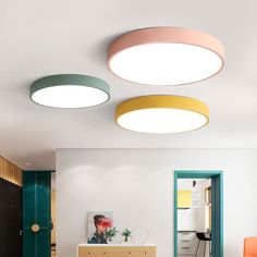 three circular lights are hanging from the ceiling in this modern living room with white walls and wood flooring