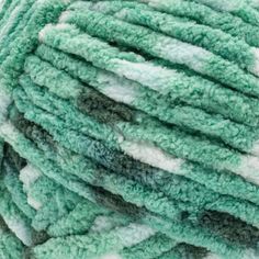 green and white yarn is piled up in the shape of a ball on top of each other