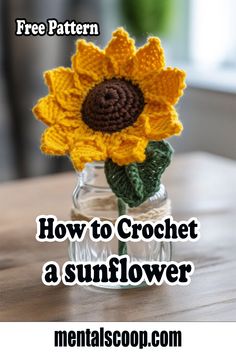 a crocheted sunflower in a small glass jar on a wooden table top