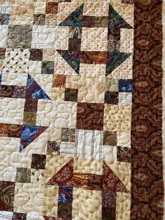 a close up of a quilt with many different designs on it, including an arrow