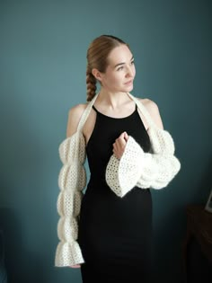 a woman wearing a black dress and white knitted shrugr