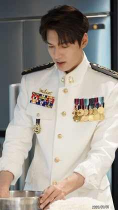 a man in uniform is preparing food on a table