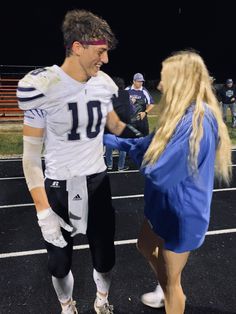 a football player is shaking hands with a woman