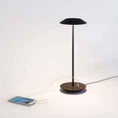 an electronic device connected to a lamp on a white surface with a phone plugged into it