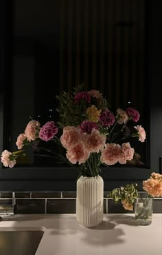 a vase filled with flowers sitting on top of a white counter next to a sink