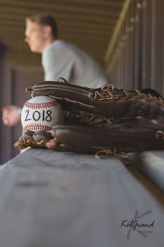 a baseball mitt and glove sitting on top of a white cloth covered bench with a man in the background