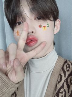 a young man with his hands in the air and painted on his face is making a peace sign