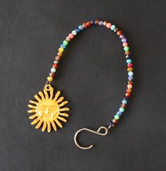 a beaded bracelet with a gold sun charm on it and a hook in the middle