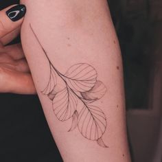 a woman's arm with a leaf tattoo on it