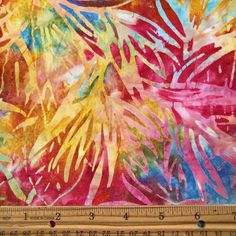 a large ruler is next to a colorful painting on fabric that has been drawn with watercolors