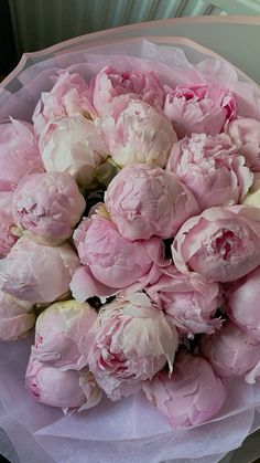 a bouquet of pink peonies sitting on top of a white tableclothed cloth