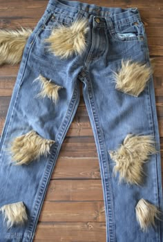 an old pair of jeans with holes and fur on the bottom, sitting on a wooden floor