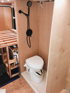 a bathroom with a toilet, shower and bunk bed in the back ground is made out of plywood planks