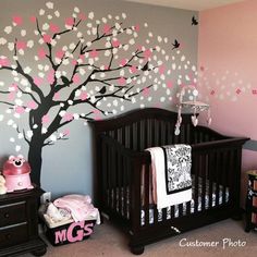 a baby's room decorated in pink and gray with a tree painted on the wall