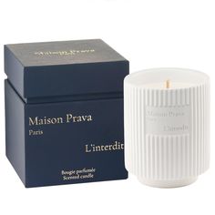 a white candle sitting next to a blue box on a white surface with the words maison prava in gold lettering