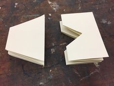 two pieces of white paper sitting on top of a wooden table next to each other