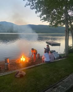 people sitting around a campfire near the water