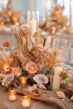 a table with candles, flowers and seashells on it is shown in this image