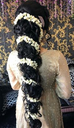 a woman with long black hair and flowers in her hair is wearing a white dress