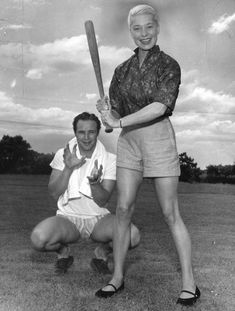 an old black and white photo of a man holding a baseball bat next to a woman