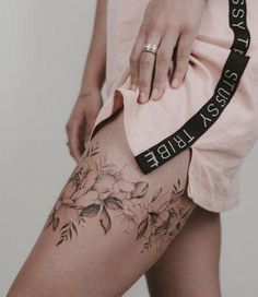 a woman's leg with tattoos and flowers on it, showing the side of her thigh