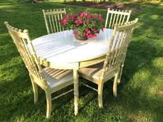 a white table with four chairs and a potted plant on it in the grass