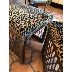 a leopard print upholstered bench and footstool in a room with tile flooring