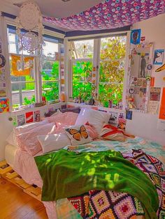 a bedroom with lots of pictures on the walls and ceiling above the bed in front of two windows