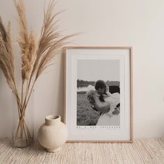 a couple kissing in front of a black and white photo next to some dried grass