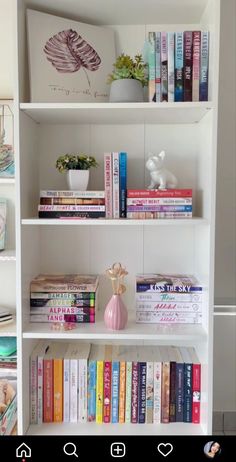 a white book shelf filled with books next to a vase and potted plant on top of it