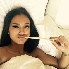 a woman laying in bed with a toothbrush in her mouth