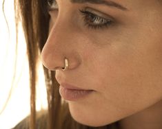 a close up of a woman with a nose piercing on her nose, looking at the camera